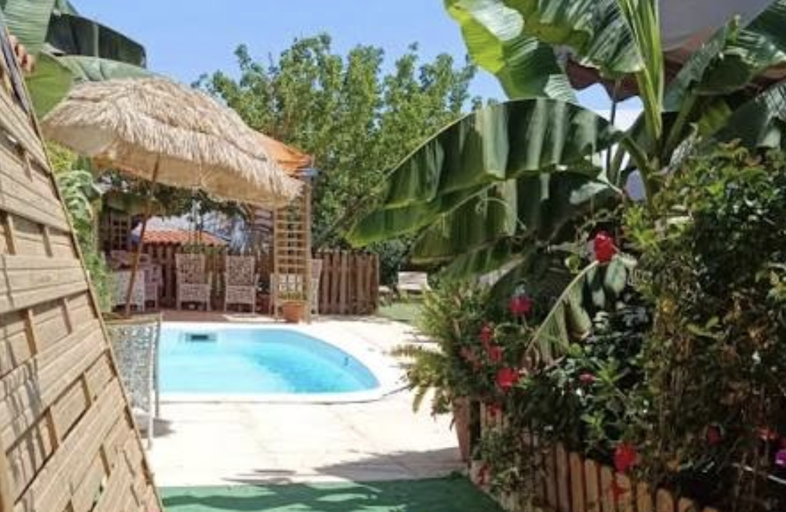 Relvado com sombra de pinheiros junto a uma piscina vedada
